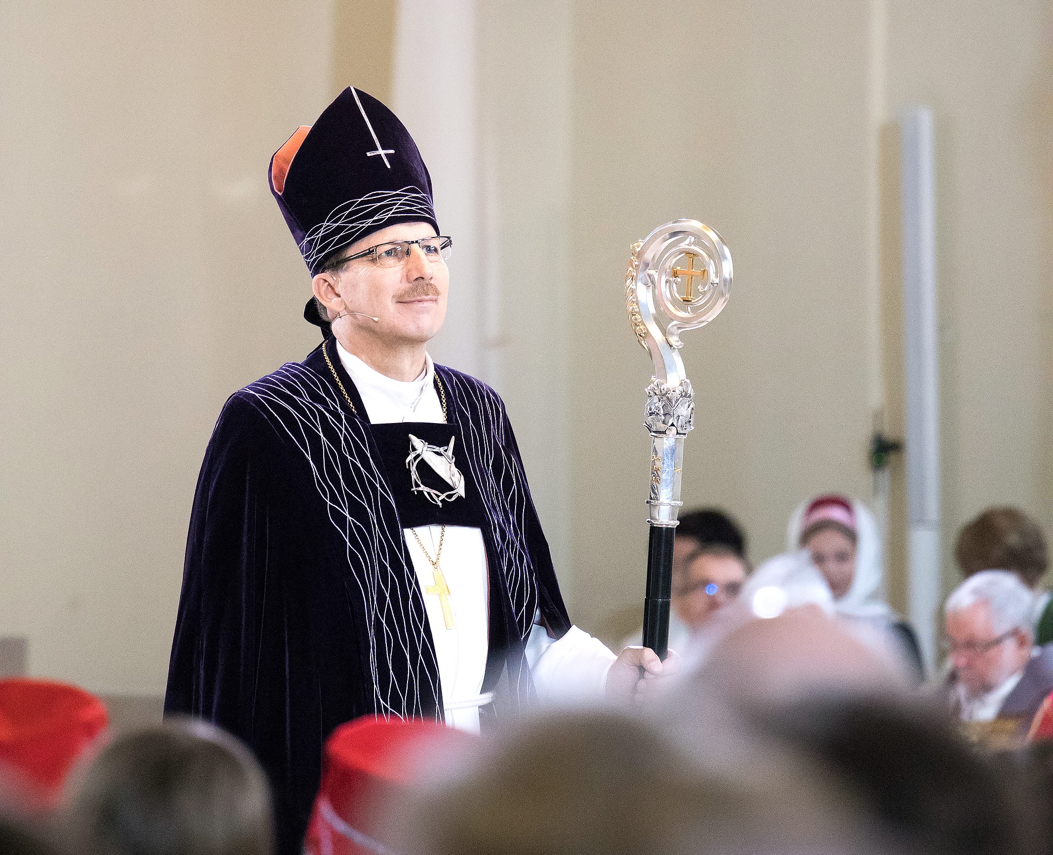 Piispa Jukka Keskitalo seisoo kirkkosalissa tummat piispanvaatteet päällä.