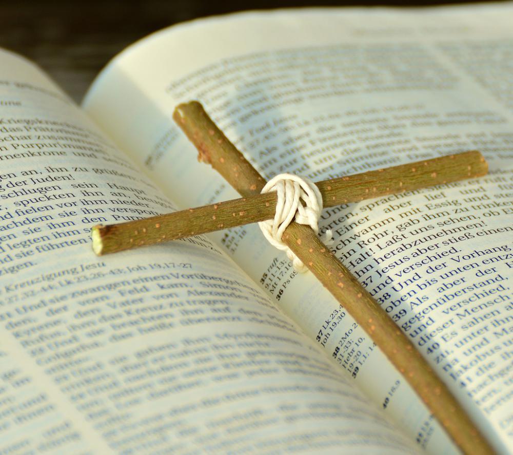 Puutikuista tehty risti avonaisen Raamatun päällä.