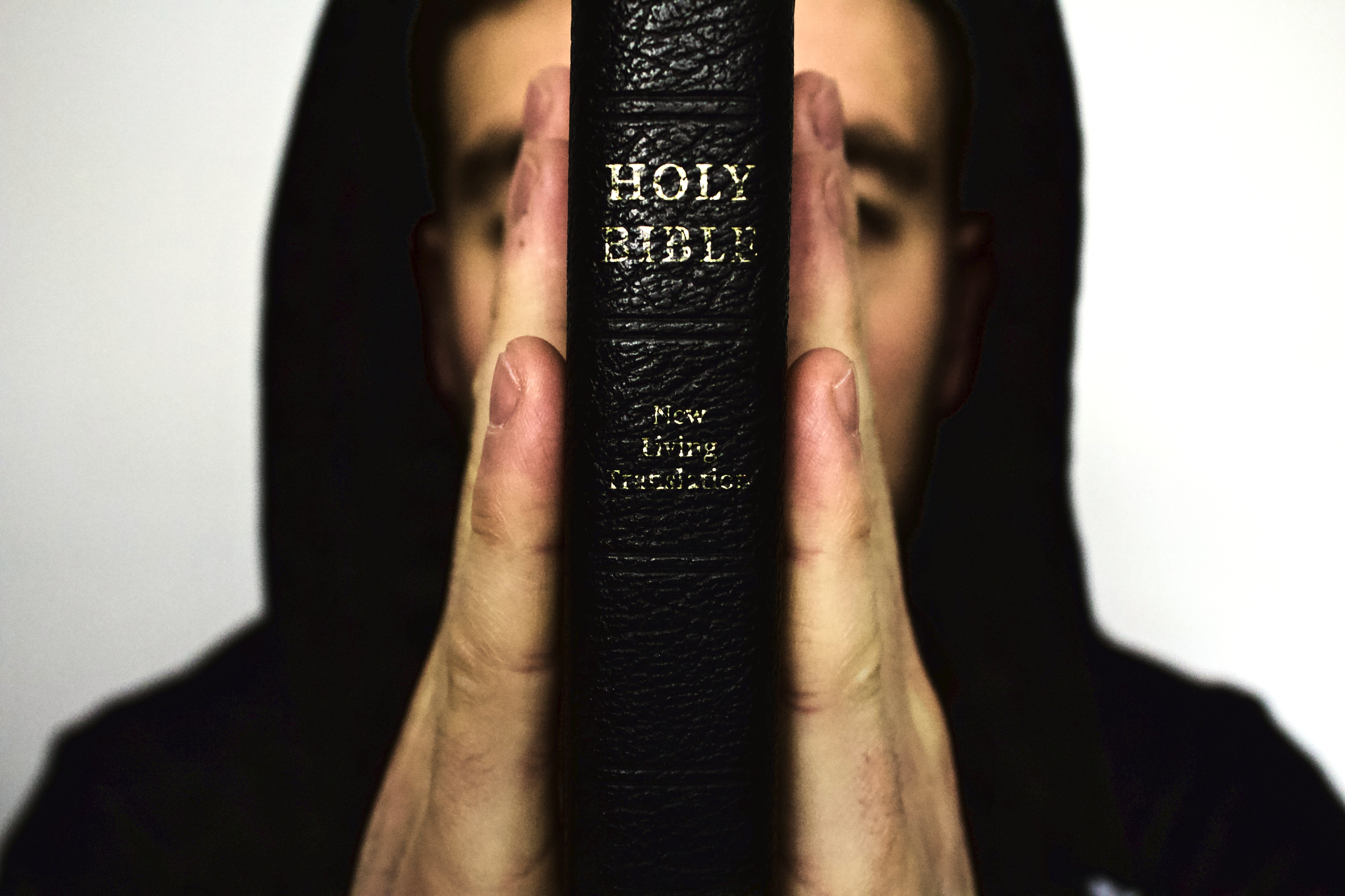 Huppariasuinen mies pitelee Raamattua käsien välissä.