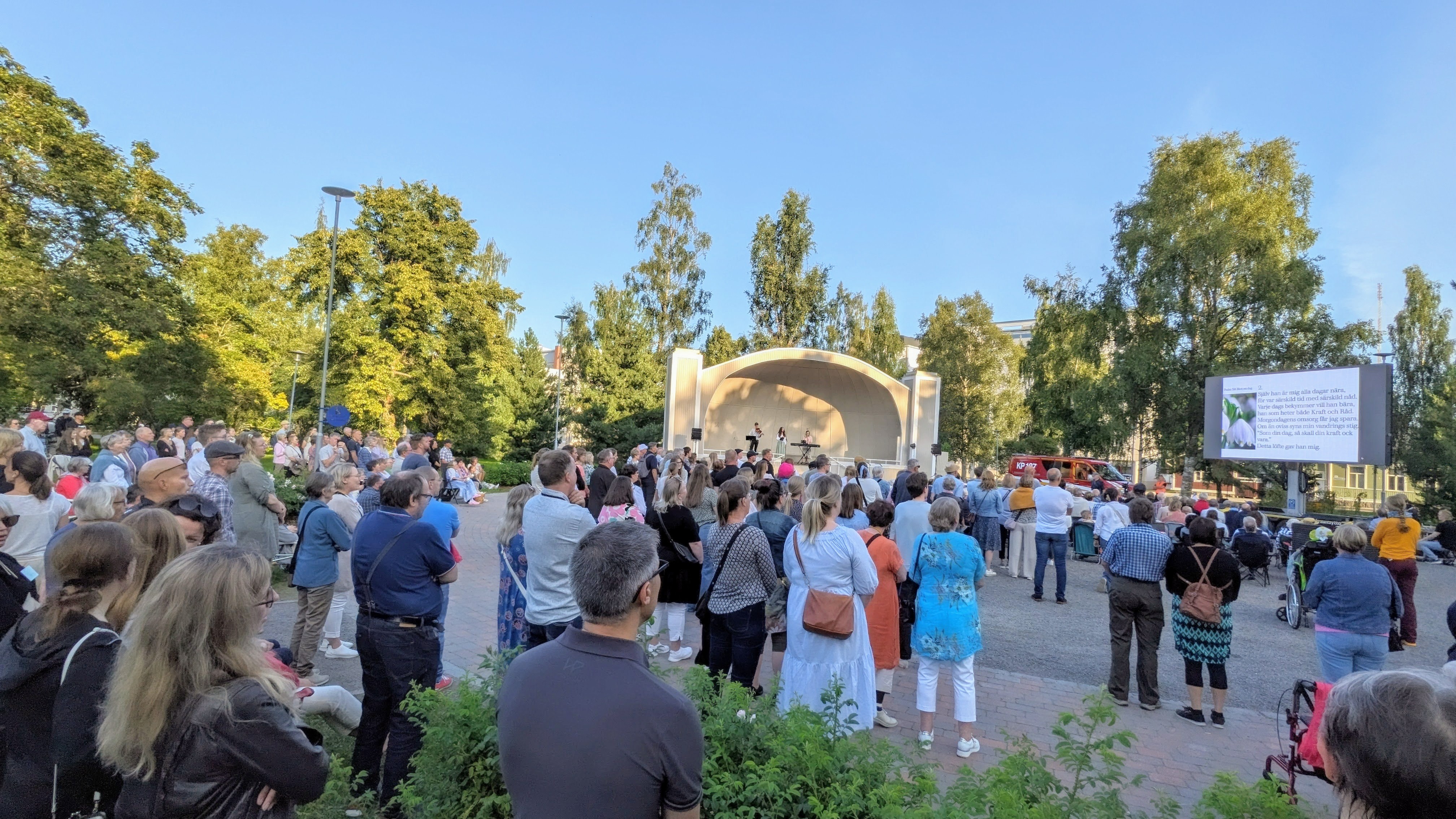 Ihmisiä seisoo puistossa laulen.