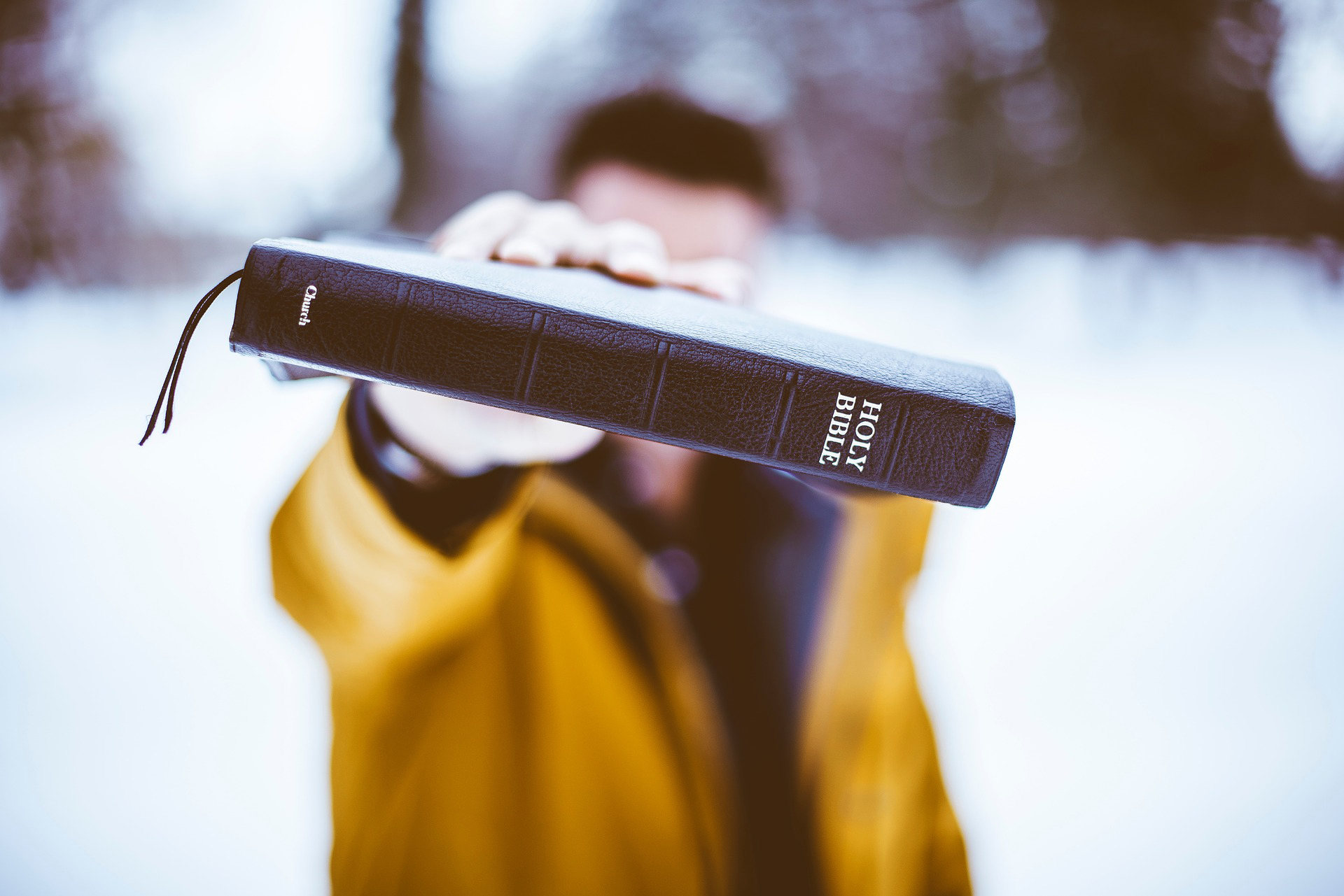 Talvimaisemassa mies näyttää kameralle Raamattua.
