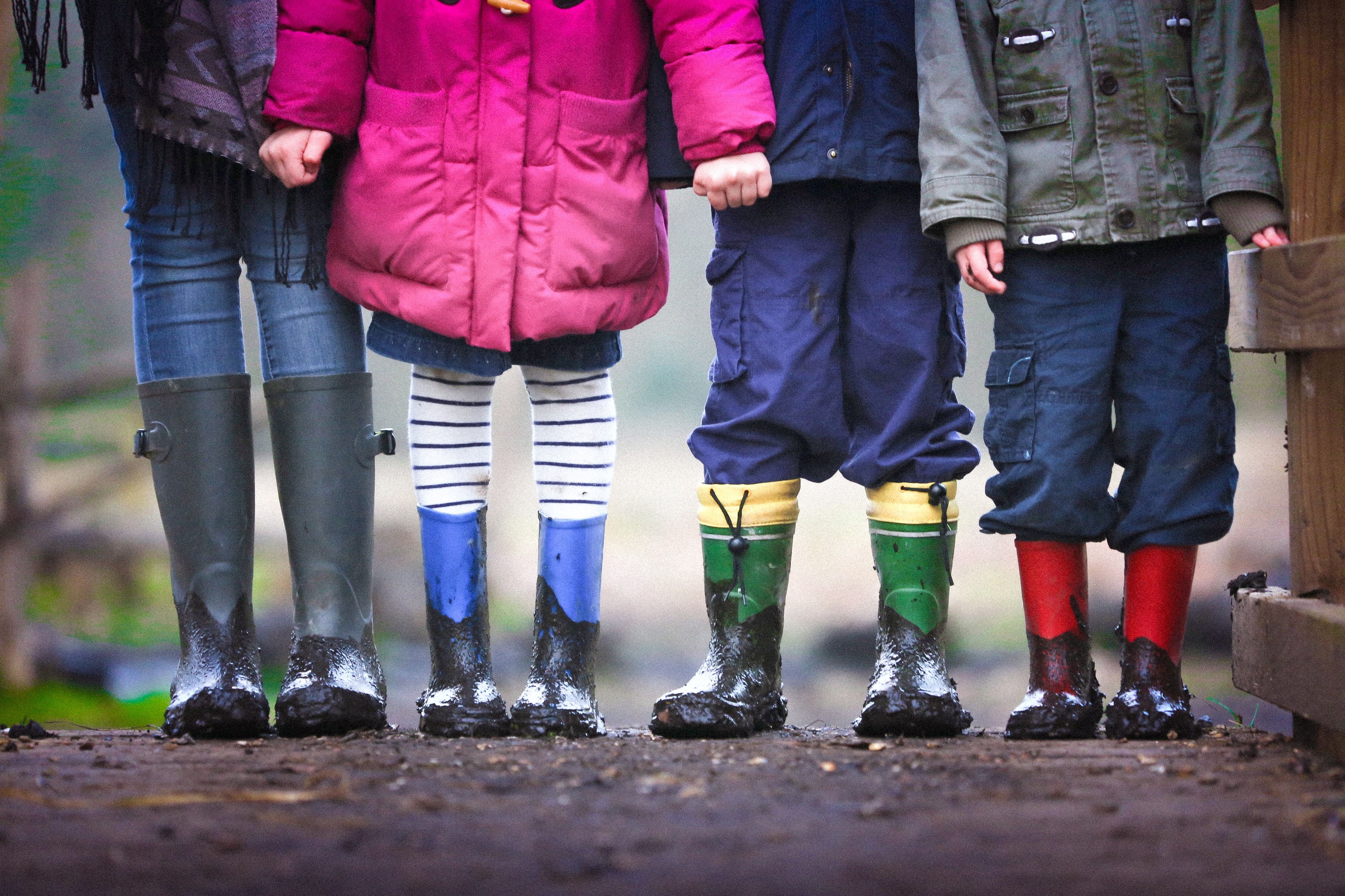 Neljän lasten jalat näkyy kumisappaat jalassa.