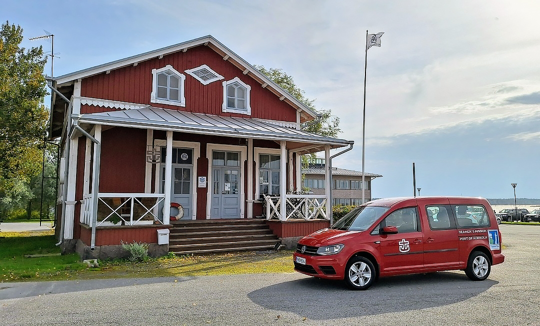Punainen merimieskirkon rakennus ja satamakuraattorin virka-auto.