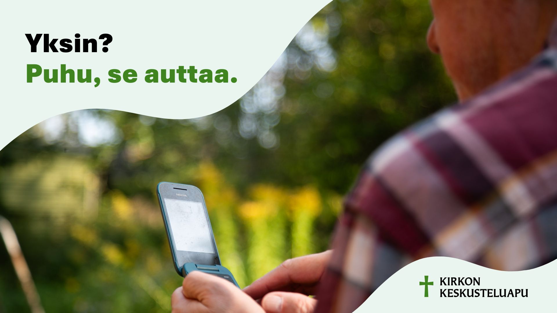 Kirkon keskusteluavun mainos, jossa ruutupaitainen henkilö näppäilee kännykkää kesäisessä maisemassa.