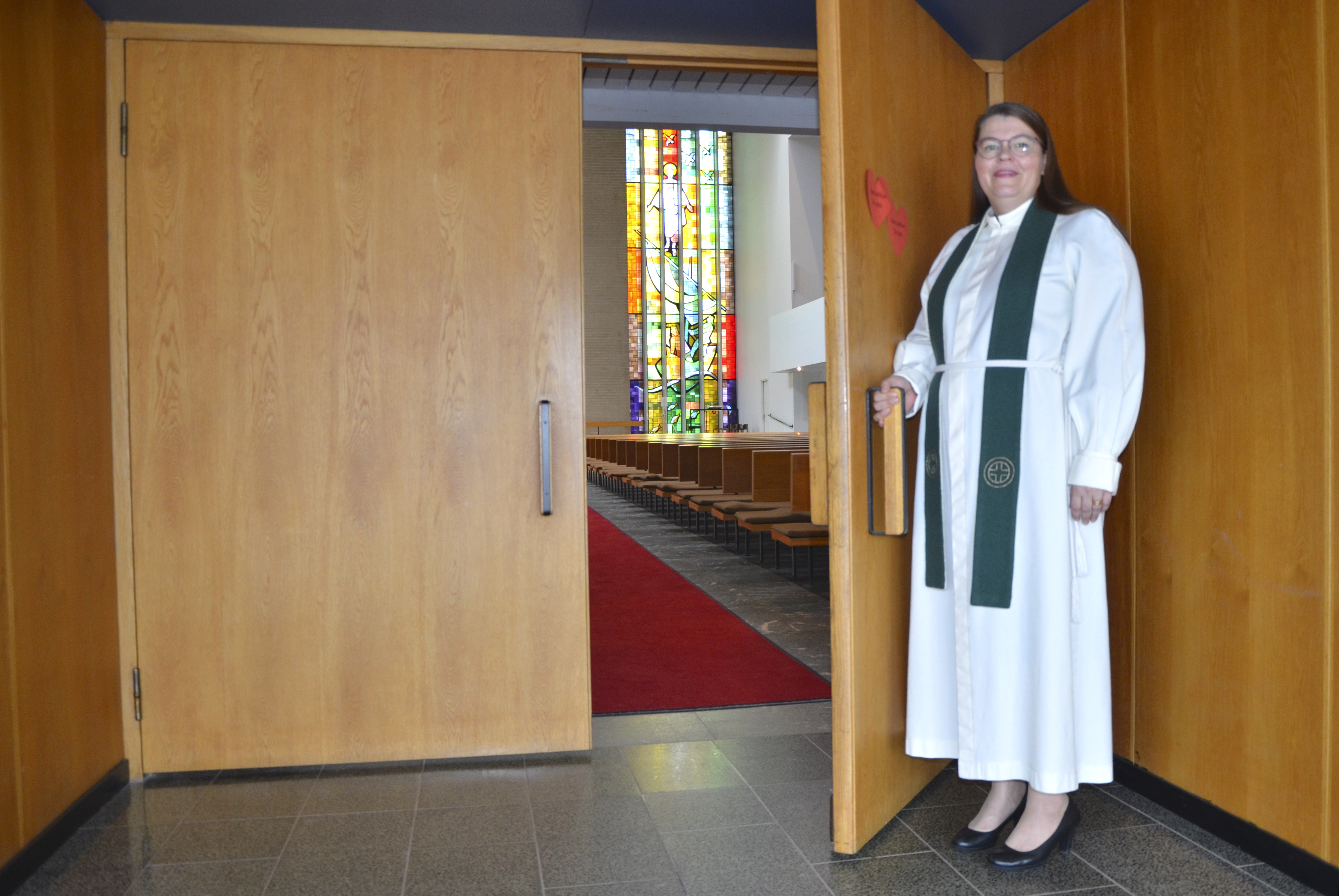Emilia Teerikangas avaa oven jumalanpalvelukseen saapuville.