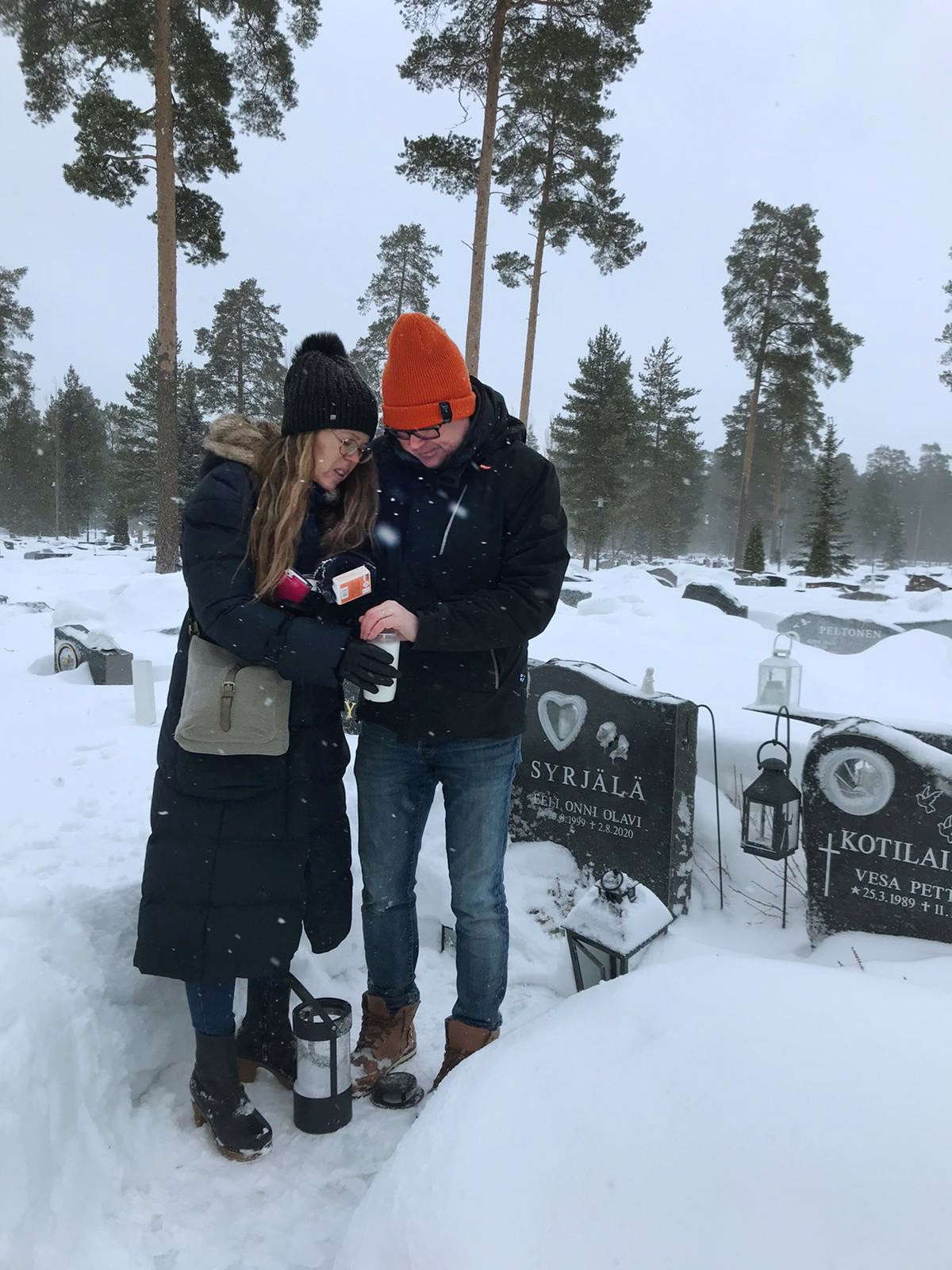 Marjo ja Tommi Syrjälä syttyävät kynttilää Eelin haudalla talvella.