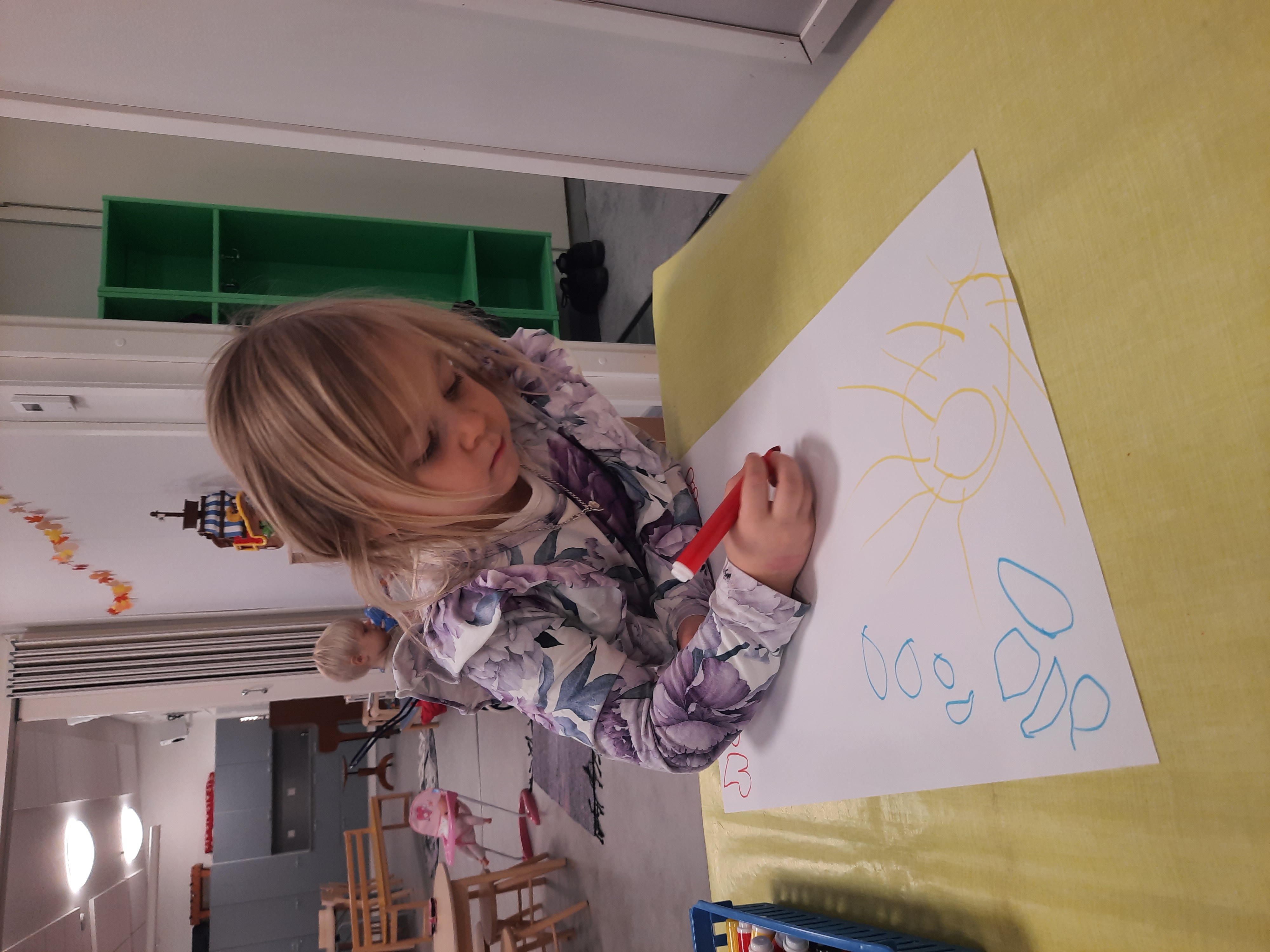 Lapsi piirtää kuvia mattoa varten.